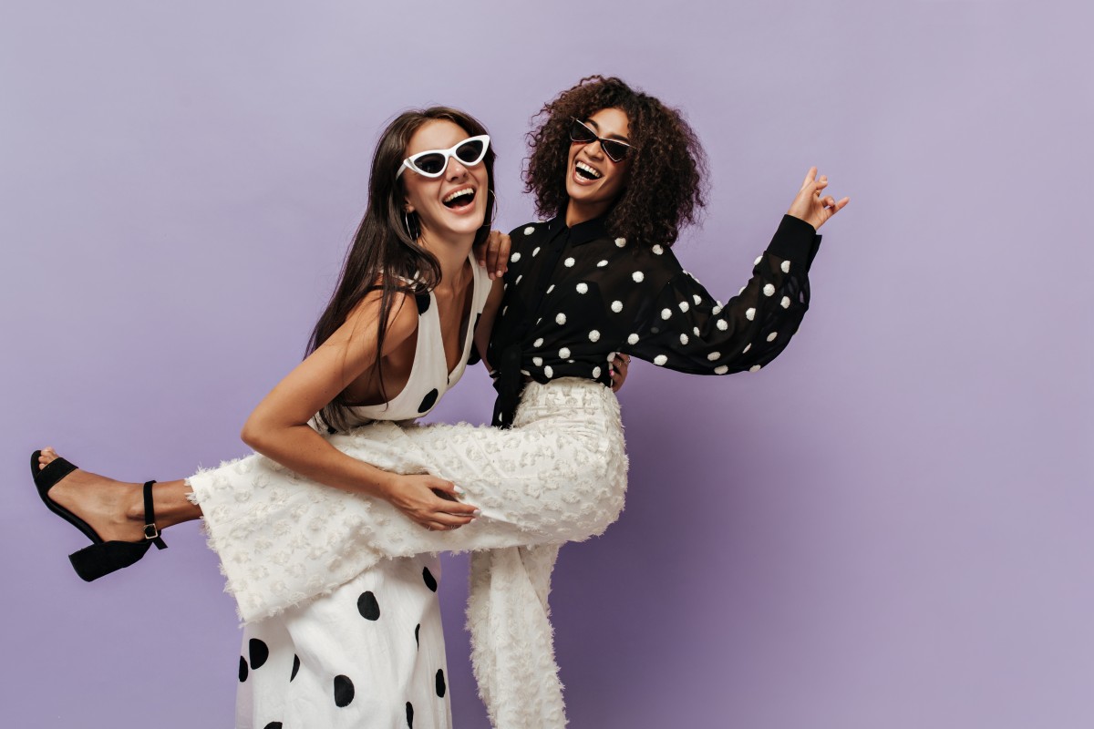 Wonderful Woman Black Blouse Trendy White Pants Laughing Having Fun With Her Friend Sunglasses Isolated Wall 1 1